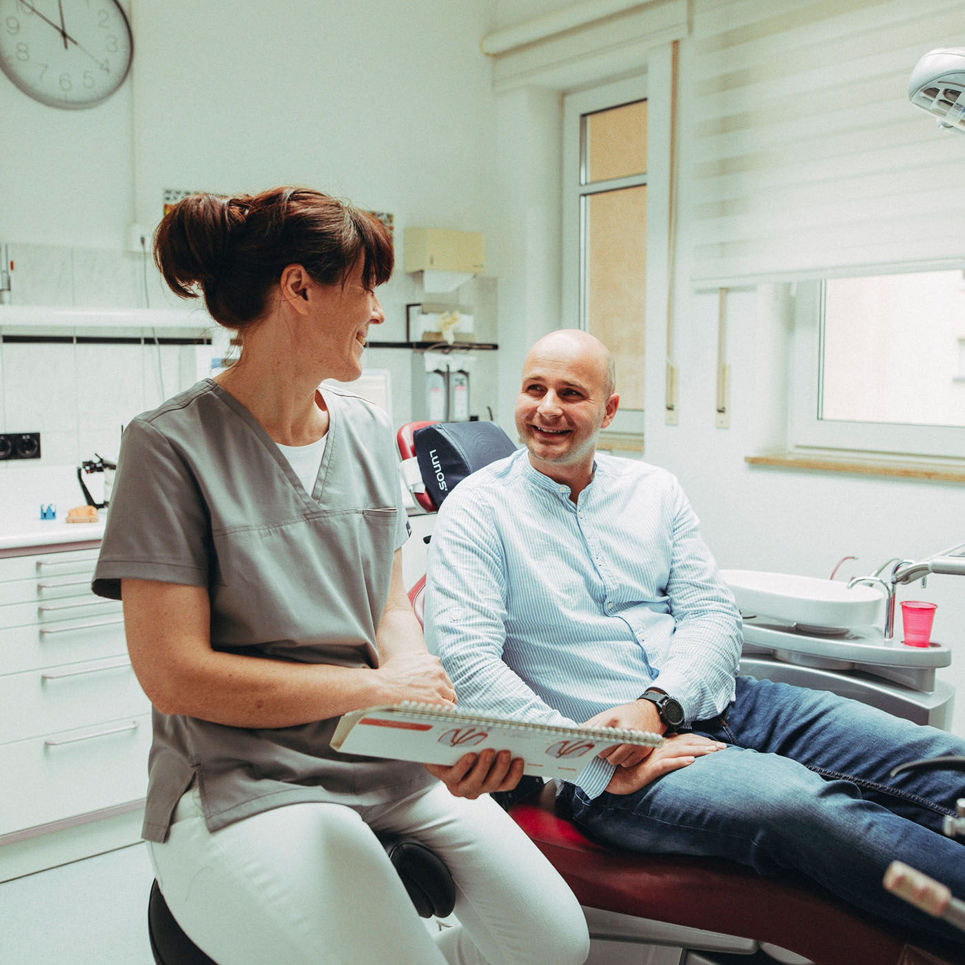 Ein Patient lacht eine Mitarbeiterin an nach einer angenehmen Zahnreinigung in der Zahnarztpraxis Christoph Bölich in Rötha.