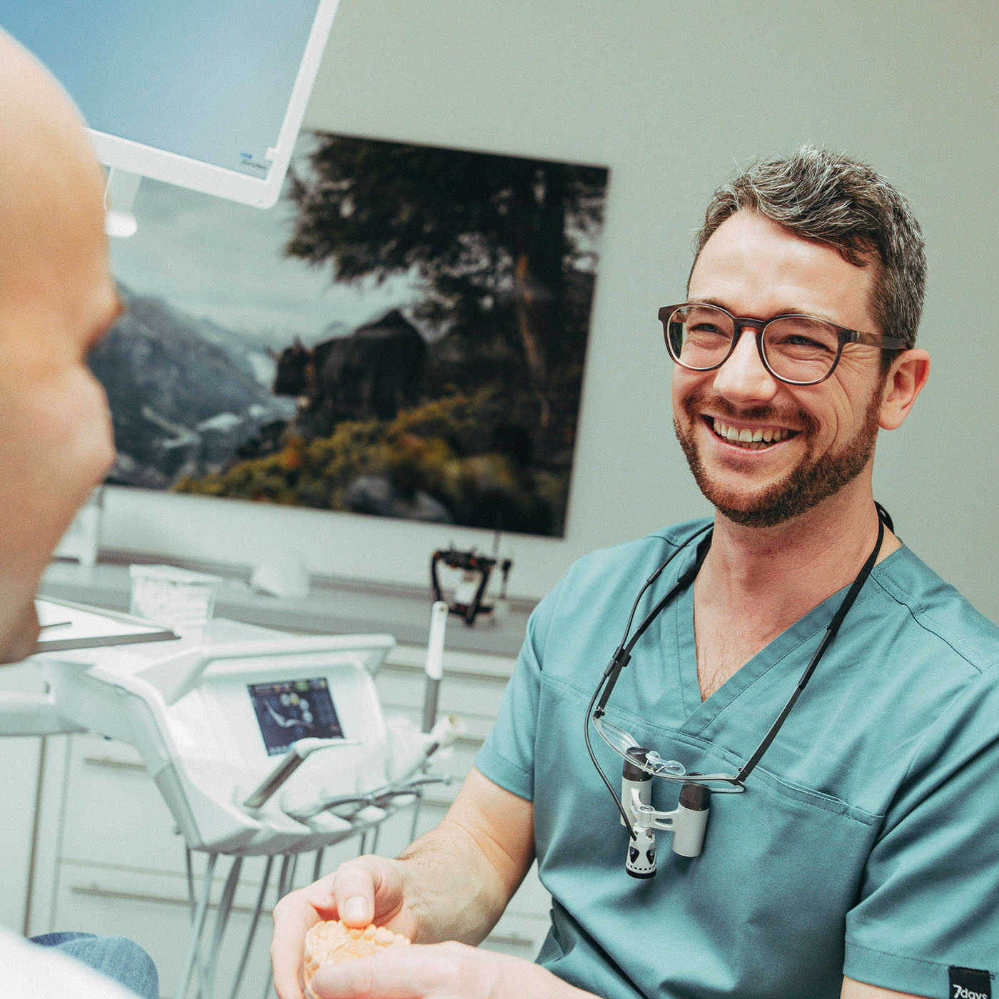 Christoph Bölich lacht herzlich einen Patienten an in der Zahnarztpraxis Christoph Bölich in Rötha.